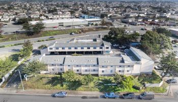 An aerial view of a building complex surrounded by roads, cars, and urban landscape in the background.